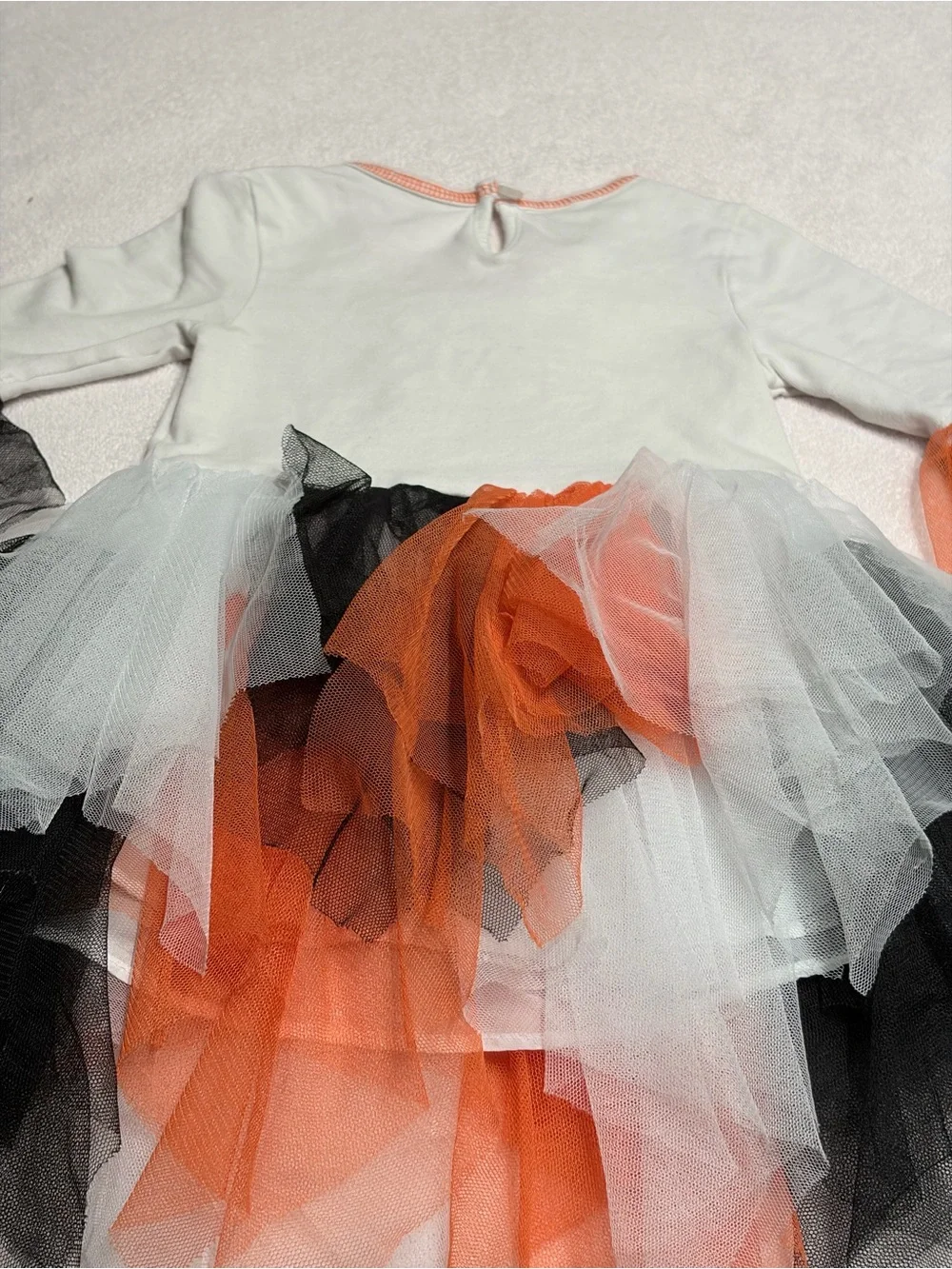 Cutie Halloween costume Has orange, black, and white tulle skirt and wrists.